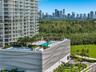 High-rise residential complex featuring an elevated pool deck, a recreational court, landscaped green space, and a decorative undulating facade