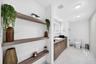 Bathroom featuring wood-finish floating shelving, wood-grain vanity cabinetry, square vessel sink, and large-format stone-tile flooring
