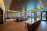 Expansive interior featuring a wood-paneled tray ceiling with recessed ambient lighting, floor-to-ceiling windows, wood-finish flooring, and a large k