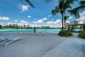 Sandy beach frontage featuring palm trees, a paved stone pathway, and an open-air pergola structure