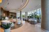 Expansive lobby featuring floor-to-ceiling glass walls, polished stone flooring, custom curved recessed ceiling lighting, and wood-paneled walls