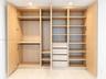 Custom floor-to-ceiling cabinetry with light wood finish, integrated hanging rods, multiple adjustable shelving tiers, and built-in drawer storage
