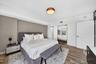 Wood-finish flooring, accent wall, and circular flush-mount ceiling lighting