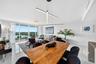 Open-concept space featuring floor-to-ceiling windows, white polished tile flooring, contemporary linear LED pendant lighting, and a glass-railed balc