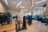 Fitness space featuring wood-finish flooring, floor-to-ceiling windows with roller shades, recessed cove lighting, suspended linear light fixtures, an