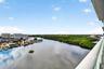 Elevated balcony featuring a glass-panel railing, expansive water frontage, and surrounding natural foliage