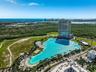 Aerial perspective featuring a high-rise residential tower and an expansive man-made crystalline lagoon with sandy shorelines