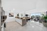 Open-concept kitchen featuring an island with wood-finish cabinetry, white flat-panel lower cabinets, stone-surfaced countertops, and polished tile fl