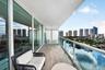 Covered balcony featuring wood-finish flooring, glass panel railings, frosted privacy screens, and floor-to-ceiling sliding glass doors