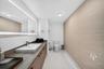 Bathroom featuring a wood-finish vanity with a rectangular vessel sink, integrated lighting mirror, stone-finish countertop, and large-format tile flo