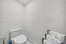 Modern white toilet with an elongated bowl and polished silver-tone hardware set against crisp neutral walls and stone-finish flooring
