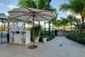 Outdoor terrace featuring large-format tile flooring, built-in towel storage console, mature palm trees, and metal fencing