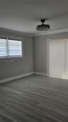 Interior room featuring wood-finish flooring, neutral wall tones, a recessed ceiling fan with integrated lighting, a sliding glass door, and a horizon