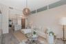 High-ceiling living area featuring clerestory windows, wood-finish flooring, a woven pendant light fixture, and an integrated kitchen with a stone-sur