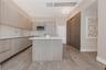 Kitchen featuring wood-finish cabinetry, stone-surface countertops, an integrated island, stainless steel appliances, and wood-finish flooring