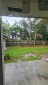 Backyard featuring a concrete patio, grass lawn, wood perimeter fencing, and mature trees
