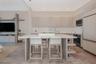 Modern kitchen featuring light wood-finish cabinetry, a large central island with a solid surface countertop, integrated stainless steel appliances, r