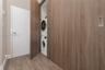 Laundry closet featuring a stackable washer and dryer unit, wood-finish cabinetry, and sliding door paneling