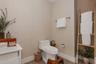 Neutral-toned wallpaper, white one-piece toilet, wood-finish flooring, and vertical wood-slat accent paneling