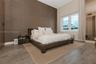 Textured accent wall, wood-finish flooring, vaulted ceiling, and full-length window treatments