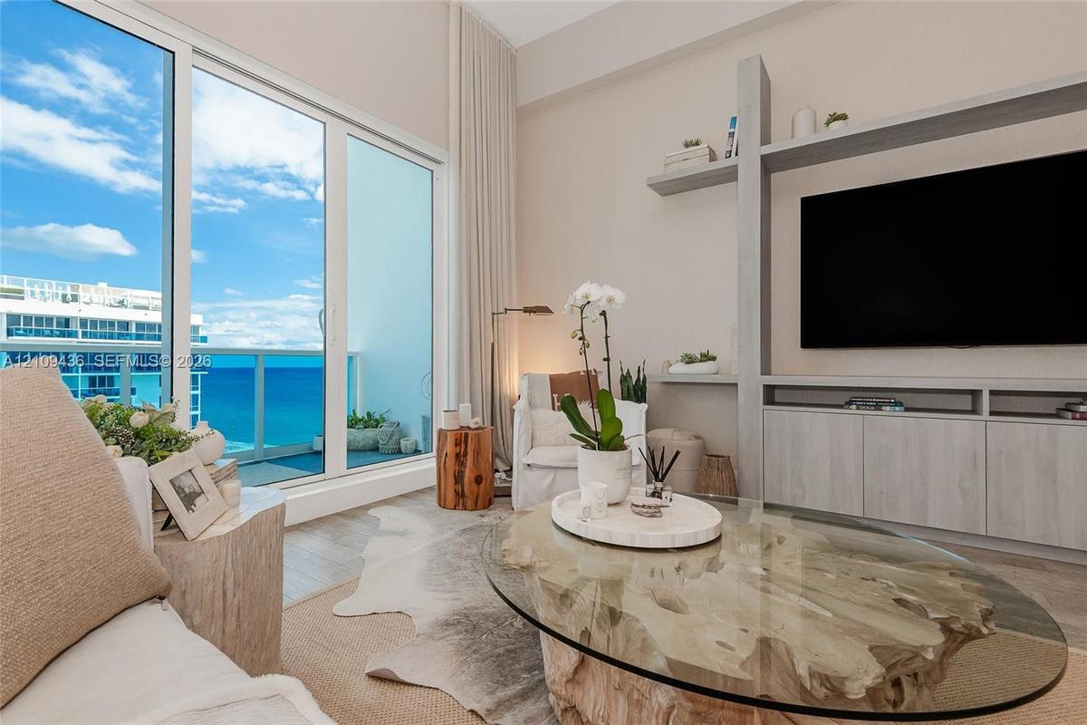 Floor-to-ceiling sliding glass doors, custom built-in media cabinetry with integrated shelving, and wood-finish flooring