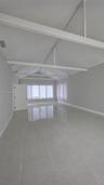 Vaulted ceiling with exposed white beams, large-format tile flooring, and multiple windows with horizontal blinds