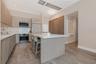 Kitchen featuring light wood-finish cabinetry, quartz countertops, a central island, stainless steel appliances, and wood-finish flooring