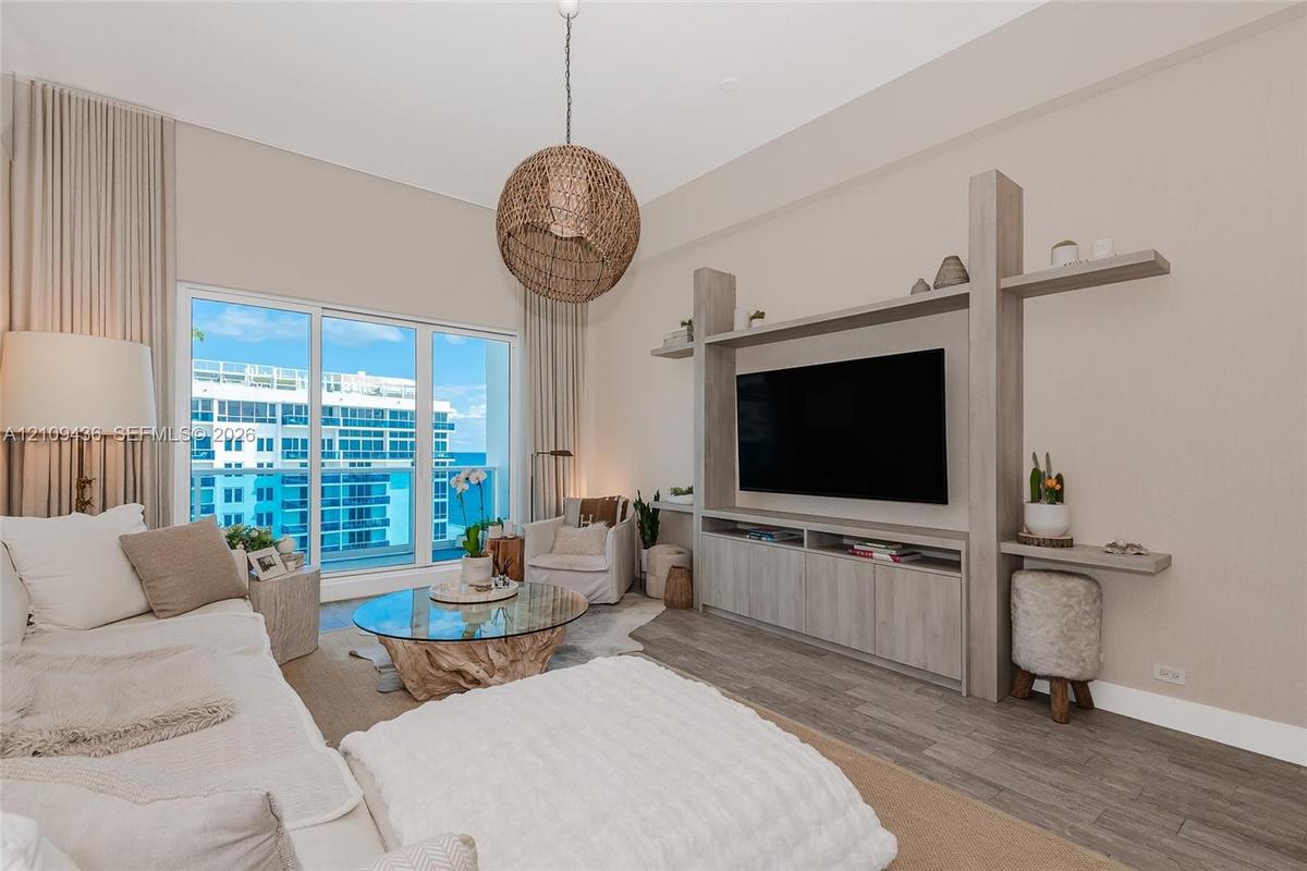 Living area featuring floor-to-ceiling sliding glass doors, custom built-in cabinetry with integrated shelving, and wood-finish flooring