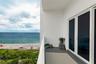 Covered balcony featuring concrete flooring, a white structural railing, and sliding glass panel doors