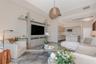 Custom built-in entertainment center with integrated shelving, wood-finish flooring, recessed lighting, and a textured pendant fixture