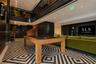Geometric patterned tile flooring, double-height ceiling with mezzanine balcony, black metal railings, recessed lighting, and built-in wall cabinetry