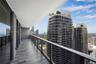 Covered balcony featuring wood-finish flooring, metal railing with glass panels, and floor-to-ceiling glass sliding doors