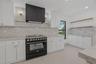 Kitchen featuring white cabinetry, stone-surface countertops, central island, black refrigerator, and multi-globe chandelier lighting