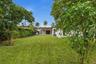 Expansive backyard featuring a large grass lawn, mature trees, and perimeter fencing