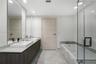 Floating double vanity with dual rectangular vessel sinks, stone-surface countertop, floor-to-ceiling mirrors, recessed lighting, and a glass-enclosed
