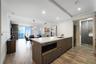 Kitchen island featuring white countertops, wood-finish cabinetry, built-in microwave, and recessed lighting