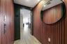Entryway featuring vertical wood-slat wall paneling, large oval wall-mounted mirror, recessed ceiling lighting, and neutral-toned wood-finish flooring