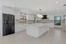 Private patio featuring large-format tile flooring, high perimeter masonry walls, a dark metal privacy fence, and wood-finish ceiling soffit