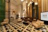 Double-height lobby featuring geometric patterned stone flooring, floor-to-ceiling mirrored paneling, and an intricate metal privacy screen