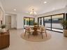 Open-concept interior featuring a center island with quartz countertops, custom white cabinetry, recessed lighting, multi-arm chandeliers, and large-f