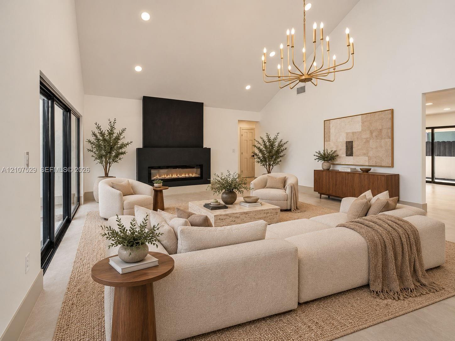 Vaulted ceiling, floor-to-ceiling windows, matte black linear fireplace, and tiered metal chandelier