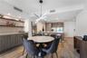 Custom wet bar featuring wood-finish cabinetry, stone-style backsplash, and floating wood shelving, complemented by wood-finish flooring, a modern geo