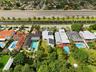 Expansive lot featuring a manicured lawn, perimeter privacy hedging, and mature trees