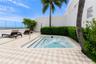 Rooftop terrace featuring an in-ground spa, patterned tile flooring, glass perimeter railing, and integrated landscaping