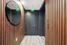 Vertical wood-slat wall paneling, light wood-finish flooring, recessed ceiling lighting, and a circular wall-mounted mirror