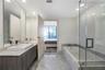 Double vanity featuring rectangular vessel sinks and stone-surround countertop, stone tile flooring, deep soaking tub, and a glass-enclosed shower