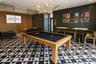 Recreational area featuring geometric tile flooring, modern gold-tone branch-style chandelier, and decorative metal screen partitions