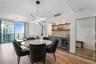 Built-in wet bar featuring stone-finish backsplash, custom cabinetry, integrated wine refrigerator, and wood shelving, complemented by wood-finish flo