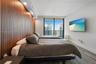 Floor-to-ceiling slatted wood-finish accent wall with integrated recessed lighting, wood-finish flooring, and large-format sliding glass door leading 