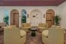 Interior space featuring rhythmic arched wood-framed doorways, recessed wall niches, wall-mounted light fixtures, and high-contrast geometric floor ti